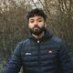 Gaailashwaran stood outside in front of some trees with a warm coat on