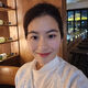 A female student stands in a restaurant and smiles at the camera. The lighting is low and behind them are bottles of wine on shelves.