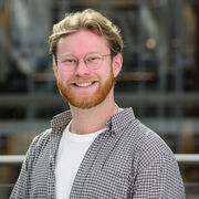 Portrait of a researcher smiling and wearing a checked shirt and glasses
