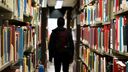 Back of male student with rucksack in library