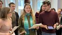 Three students rehearsing their lines. They have their scripts in their hands 