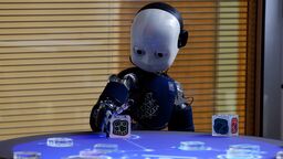 A little robot with a white face interacting with a cube. 