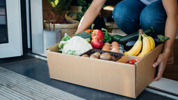 Cropped shot of young woman receiving a box of fresh organic food delivery at the front door.