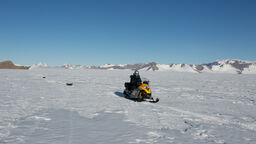 A snowmobile travelling across Antarctica with a radar survey attached to locate and examine subglacial lakes