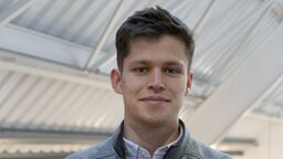 Tobias Darroach wearing a white shirt and a grey jumper.