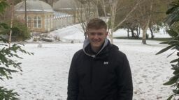 A man standing in the snow, framed by tree branches