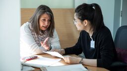 Two women talking at a table with paperwork