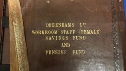 An old weathered leather book with the text 'Debenham Ltd Workroom Staff (Female) Savings Fund and Pension Fund' on the cover